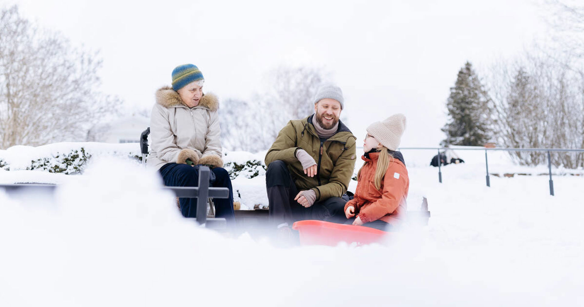 Vanhus, aikuinen ja lapsi juttelevat ulkona talvella.