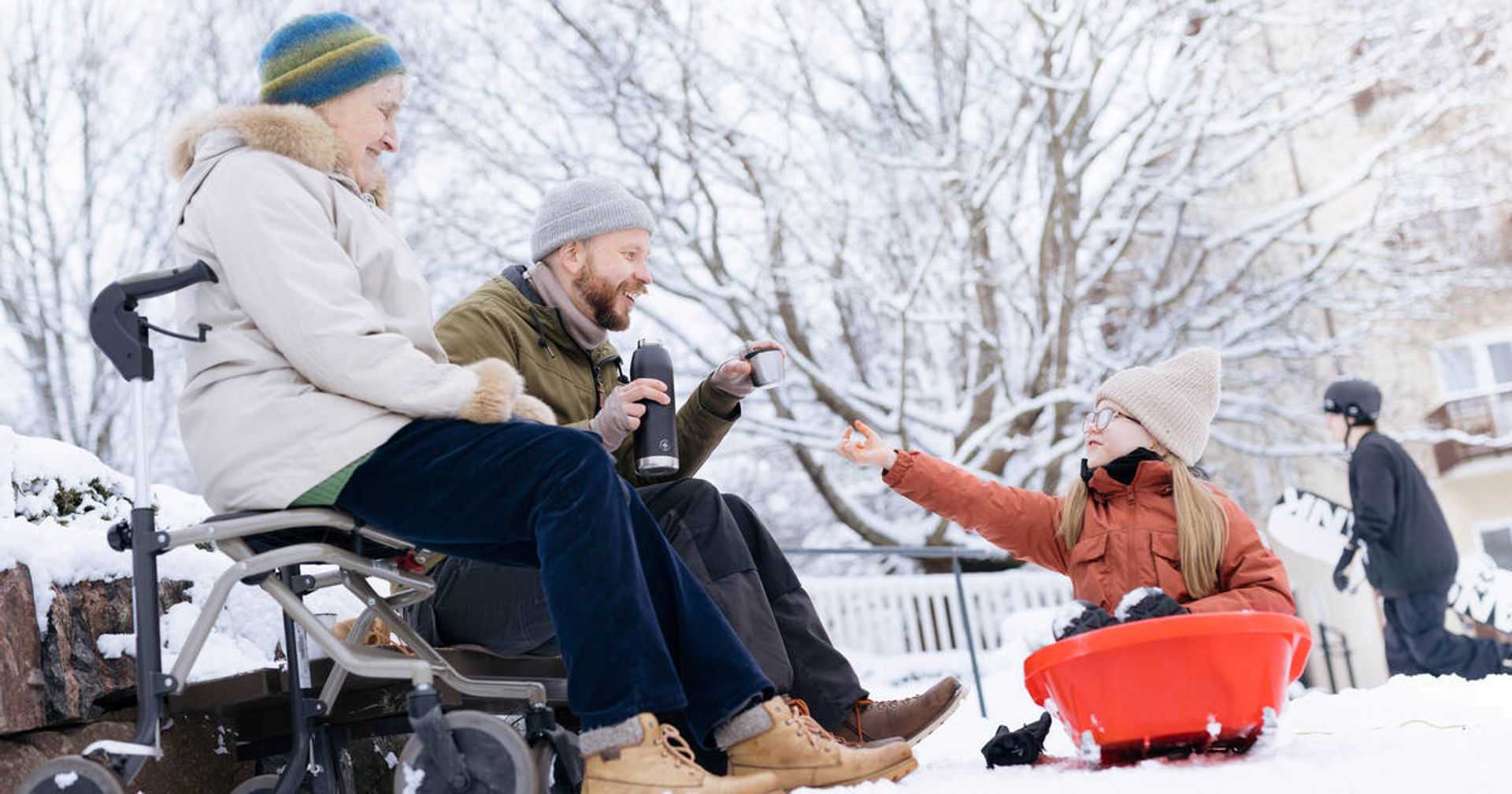 Aikuinen, vanhus ja lapsi pulkassa syövät ulkona eväitä.