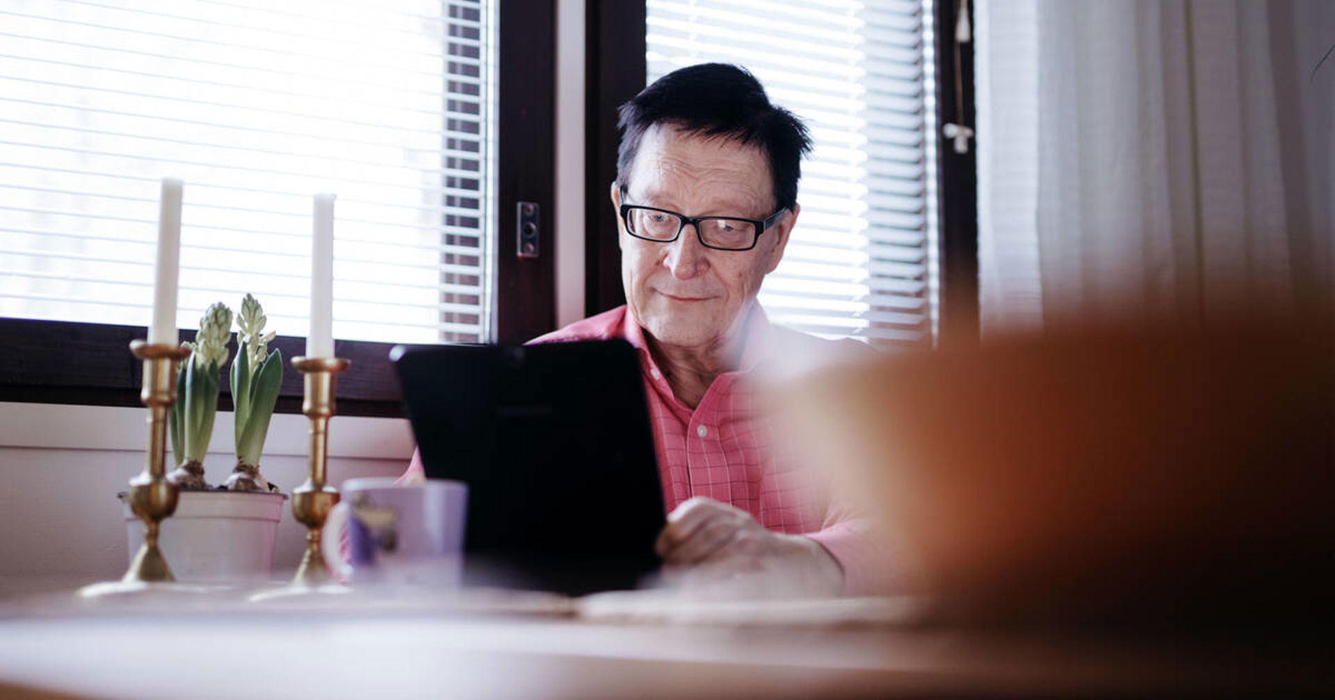 Henkilö katsoo kannettavaa tietokonetta keittiössä.