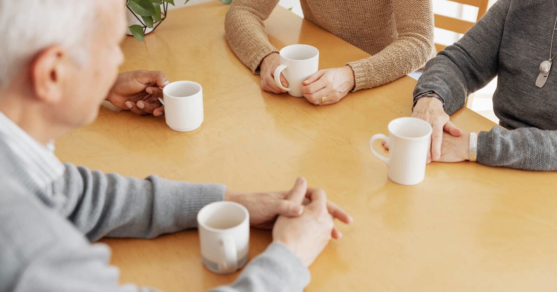Neljät kädet ja kahvikupit pöydällä.